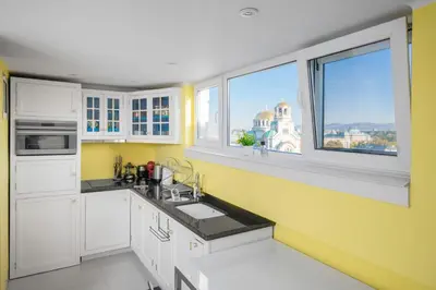 a kitchen with yellow walls and white cabinets and windows at Best Views from Top Central Cozy 1-Bedroom Flat by Flat Mаnager in Sofia