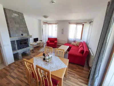 a living room with a red couch and a table at Pirin Heights Apartment 200m from SKI ROAD in Bansko