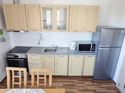 a kitchen with wooden cabinets and a stainless steel refrigerator at Pirin Heights Apartment 200m from SKI ROAD in Bansko