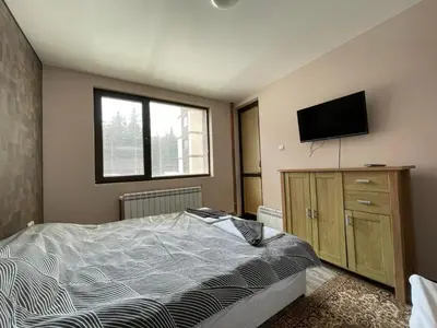 a bedroom with a bed and a flat screen tv at Комплекс Свети Георги in Pamporovo