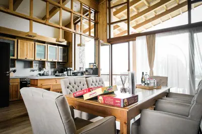 a kitchen with a wooden table with chairs and a counter at Pirin Golf Villa Relax in Razlog