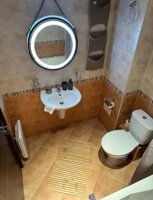 a bathroom with a toilet and a sink and a mirror at Top location unique apartment in Bansko