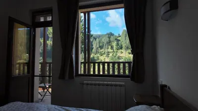 a bedroom with a view of a mountain from a window at Стаи за гости Куцеви in Devin