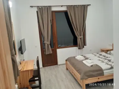 a bedroom with a bed and a desk and a window at Стаи за гости Куцеви in Devin