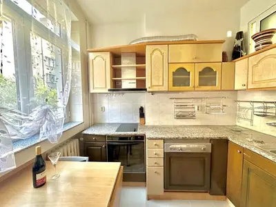 a kitchen with wooden cabinets and a table with a bottle of wine at Venelin Apartment in Sofia