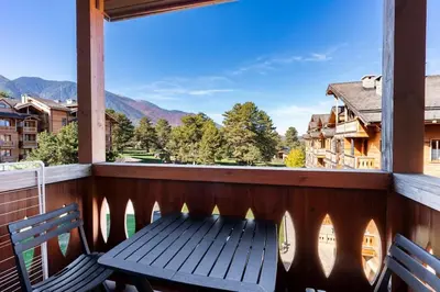 a bench on a balcony with a view of the mountains at Pirin Golf & Country Club Apartment in Bansko