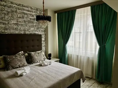 a bedroom with a bed with green curtains and a window at Бутиков Семеен Хотел БРИО in Velingrad