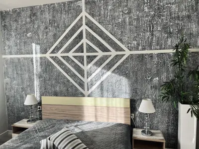 a bedroom with a bed and a gray wall at Бутиков Семеен Хотел БРИО in Velingrad