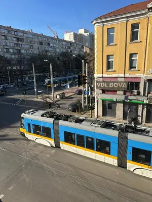 a blue and yellow train on a city street at Lions Bridge C-E-N-T-R-A-L in Sofia