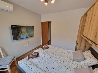 a bedroom with a bed and a tv on the wall at Two-bedroom Apartment Paskalina, near the Ski lift in Bansko