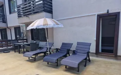 a group of chairs and an umbrella in a patio at Two-bedroom Apartment Paskalina, near the Ski lift in Bansko