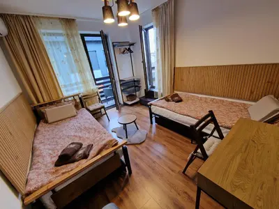 a room with two beds and a table and chairs at Two-bedroom Apartment Paskalina, near the Ski lift in Bansko