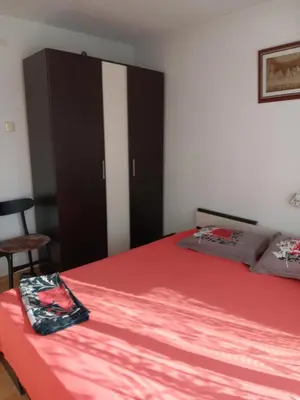 a bedroom with a bed with red sheets and a cabinet at Apartment Friends in Sandanski