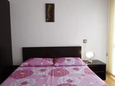 a bed with a purple bedspread with flowers on it at Apartment Friends in Sandanski