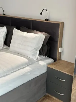 a bed with a wooden headboard and a nightstand next to it at Vimar Apartments in Panagyurishte