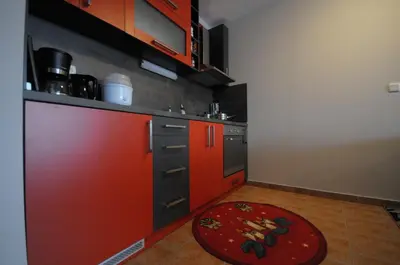 a kitchen with red cabinets and a red rug at Penthouse 2 Bedroom Apartment w fireplace in Bansko