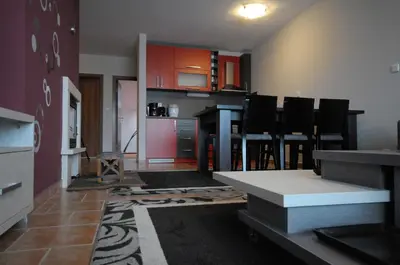 a living room with a kitchen with orange cabinets at Penthouse 2 Bedroom Apartment w fireplace in Bansko