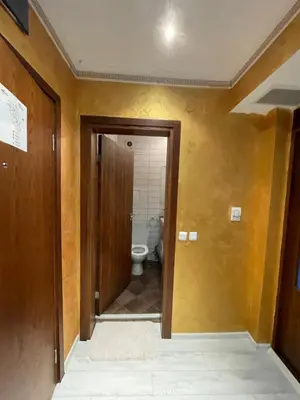 a hallway to a bathroom with a toilet in it at English Apartments in Bansko