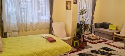 a bedroom with a yellow bed and a couch at Peaceful studio in the city center, close to subway, Medical University in Sofia