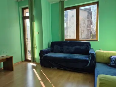 a living room with a black leather couch and windows at Apartment Niko in Bansko
