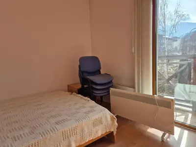 a bedroom with a chair and a bed and a window at Apartment Niko in Bansko