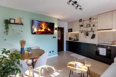 a kitchen with a table and a fireplace on the wall at The Snowmad Nest - Valentina Heights, 8 min from the gondola in Bansko