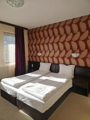 a bedroom with a large bed with a large headboard at Хотел Релакс in Velingrad