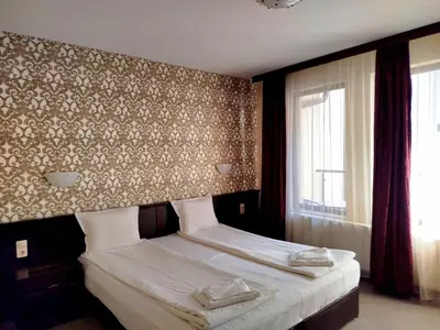 a bedroom with a bed with two towels on it at Хотел Релакс in Velingrad