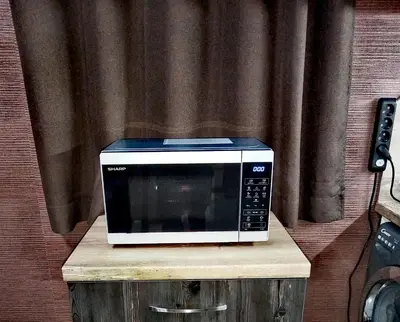 a microwave sitting on top of a wooden stand at Апартамент за гости в Пампорово in Pamporovo