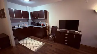 a kitchen with brown cabinets and a flat screen tv at Florimont Heights Apart Complex in Bansko