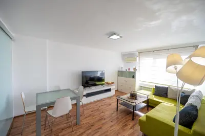 a living room with a green couch and a table at Bright 1BDR with Balcony in Sofia