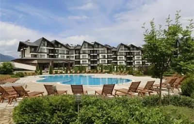 a resort with a pool and chairs and a building at Aspen Golf Apartment with Stunning Mountain View in Bansko
