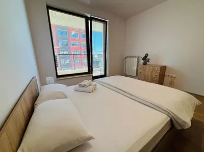a bedroom with two beds and a large window at Bright New Apartment With Parking At The Center! in Sofia