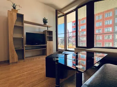 a living room with a tv and some windows at Bright New Apartment With Parking At The Center! in Sofia