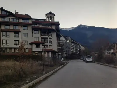 a building on the side of a road with cars parked at Apartment Melania in Complex Royal Towers in Bansko