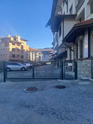 a fence in front of a building with a parking lot at Apartment Melania in Complex Royal Towers in Bansko