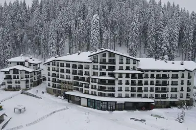 a large building in the snow with snow covered trees at Прекрасно място за нощувки в Пампорово in Pamporovo