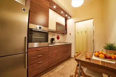 a kitchen with wooden cabinets and a table with a bowl of fruit at Central Luxury Cozy Modern Apartment in Sofia