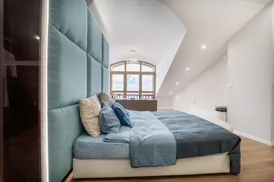 a bedroom with a large bed with a blue headboard at Host2U Penthouse Sauna, Jacuzzi, Fireplace in Bansko