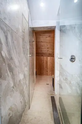 a bathroom with a walk in shower with a glass door at Host2U Penthouse Sauna, Jacuzzi, Fireplace in Bansko