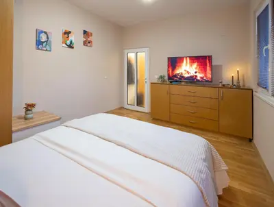 a bedroom with a bed and a tv on a dresser at Groovy Olive Apartment in Troyan