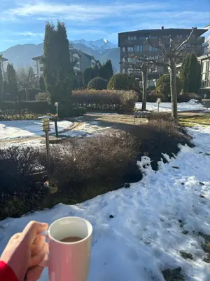 a person holding a cup of coffee in the snow at Aspen golf & Ski resort 2 bedroom apartment E002 in Razlog