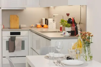a white kitchen with a table with wine glasses at Elit Park apartment Bright & Cozy in Plovdiv