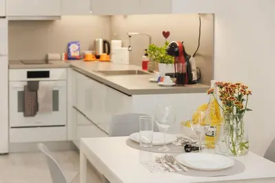 a white kitchen with a table with wine glasses at Elit Park apartment Bright & Cozy in Plovdiv