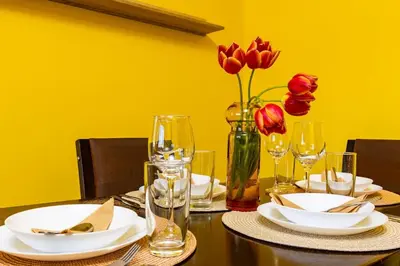 a table with plates and wine glasses and red roses at City Center Apartment Aleko Konstantinov in Plovdiv