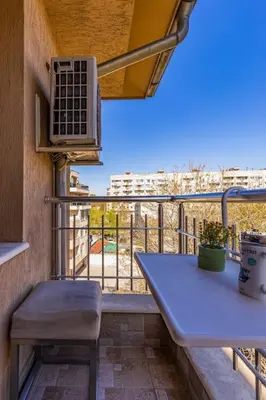 a balcony with a table and a view of a city at City Center Apartment Aleko Konstantinov in Plovdiv