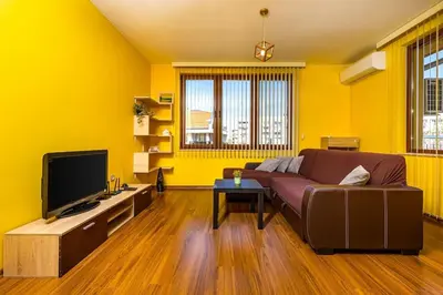 a yellow living room with a couch and a tv at City Center Apartment Aleko Konstantinov in Plovdiv