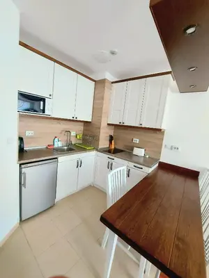 a kitchen with white cabinets and a wooden table at BELVEDERE Holiday Club VIP 59 in Bansko