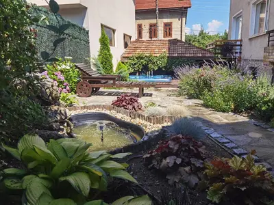 a garden with a pond in front of a house at Mira Guest House in Dobrinishte