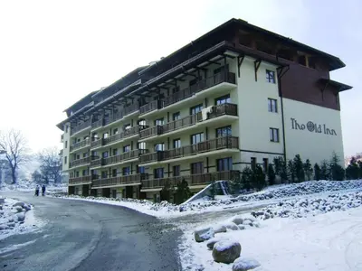 a large building on a snow covered road at Cozy 2-Bedroom Stay with Parking in OLD INN Bansko by Flat Mаnager in Bansko